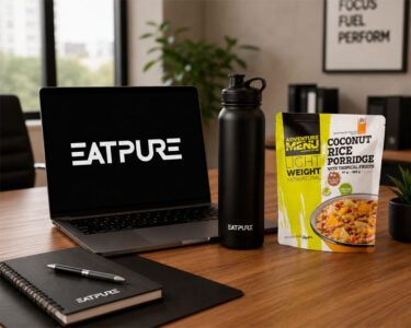 Comida liofilizada: Comidas prácticas para viajes, acampadas y días intensos Comida liofilizada de Adventure Menu preparada en un escritorio con un portátil y una botella de EatPure